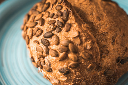 A loaf of rye bread on a turquoise or blue plate on a brown background. Close-up. Top view, Space for text. High quality photoの写真素材