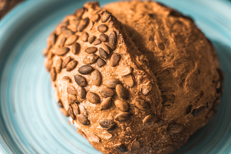 A loaf of rye bread on a turquoise or blue plate on a brown background. Close-up. Top view, Space for text. High quality photoの写真素材