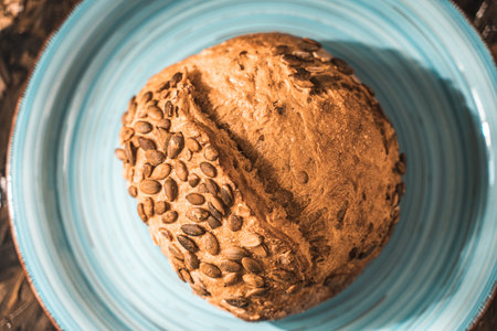 A loaf of rye bread on a turquoise or blue plate on a brown background. Close-up. Top view, Space for text. High quality photoの写真素材