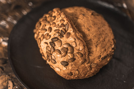 A loaf of rye bread on a black plate on a brown background. Close-up. Top view, space for text. High...