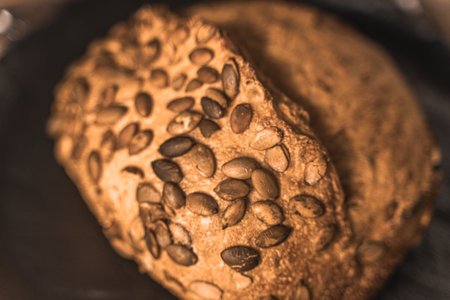 A loaf of rye bread on a black plate on a brown background. Close-up. Top view, space for text. High quality photoの写真素材