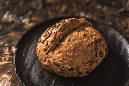 A loaf of rye bread on a black plate on a brown background. Close-up. Top view, space for text. High quality photoの写真素材
