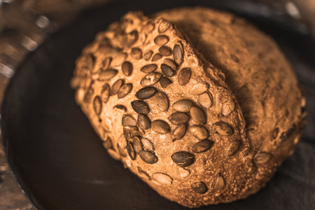 A loaf of rye bread on a black plate on a brown background. Close-up. Top view, space for text. High quality photoの写真素材