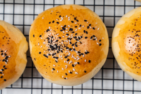 Buns with sesame seeds on a black grill on a white background. View from above. High quality photo