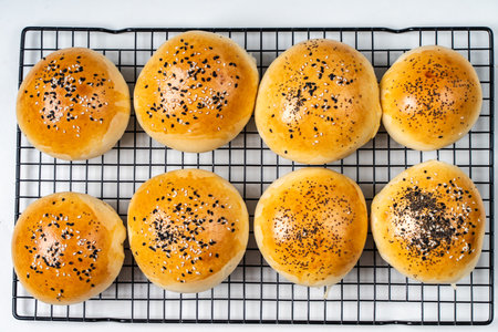Buns with sesame seeds on a black grill on a white background. View from above. High quality photoの写真素材