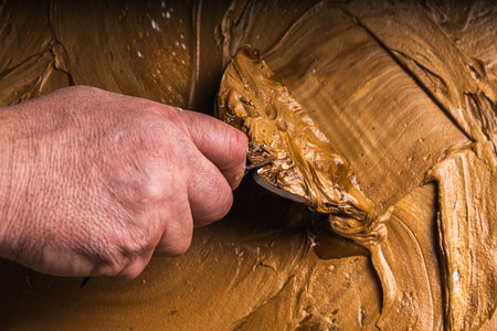 A man's hand applies brown plaster to the wall. Close-up. High quality photoの写真素材