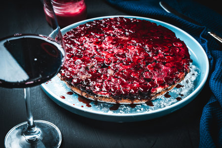 Delicious cherry clafoutis or French berry pie and a glass of red wine on a black background with a blue napkin. High quality photoの写真素材