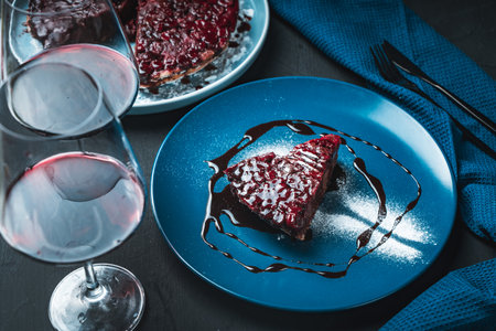 Delicious cherry clafoutis or French berry pie and a glass of red wine on a black background with a blue napkin. High quality photoの写真素材