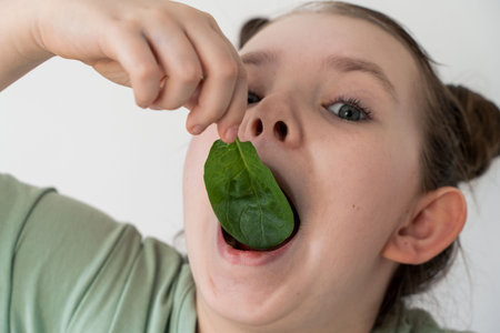 Little girl eating spinach. Concept of healthy food and vitamins. Selected focus. Close-up. High quality photoの写真素材