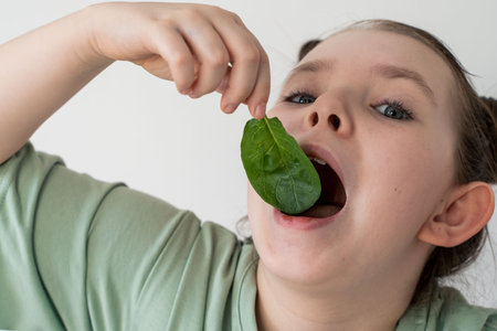 Little girl eating spinach. Concept of healthy food and vitamins. Selected focus. Close-up. High quality photoの写真素材