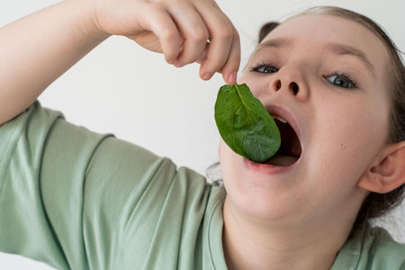 Little girl eating spinach. Concept of healthy food and vitamins. Selected focus. Close-up. High quality photoの写真素材