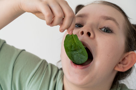 Little girl eating spinach. Concept of healthy food and vitamins. Selected focus. Close-up. High quality photoの写真素材
