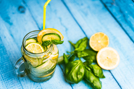 A summery, refreshing cucumber and basil cocktail in a transparent glass mug on a blue wooden table. Selected focus. High quality photoの写真素材