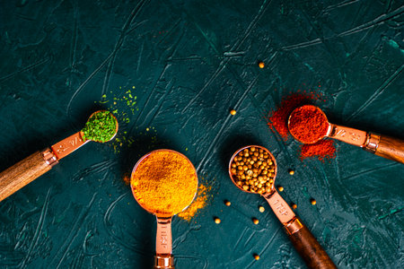 Spices in copper measuring spoons on a malachite textured background. Bright turmeric, paprika, parsley and coriander. View from above. Close-up. High quality photoの写真素材