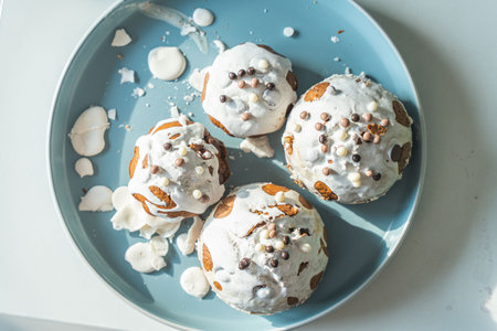 Muffins or cupcakes covered with white frosting and chocolate balls on a light blue plate on a white background. View from above. High quality photoの写真素材