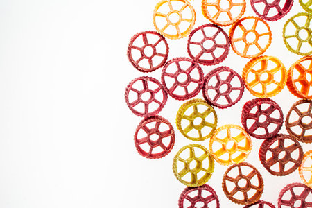 Dry pasta Rotelle on white background in the form of a frame. Different flavors and color: egg, spinach, carrot, pepper. Space for text. Flat lay. Top view. High quality photoの写真素材