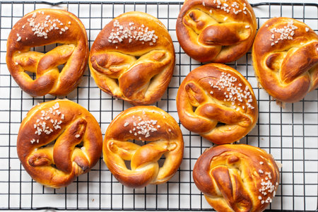 Appetizing pretzels, pretzels or buns with coarse salt on a black grill on a white background. Top...