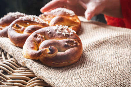 A womans hand in out-of-focus reaches for a pretzel on a canvas on a wicker basket. Selected focus....