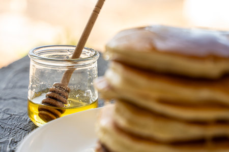 Pancakes poured with honey on a white plate with napkin and coffee on a gray background. Selected Focus. High quality photoの写真素材