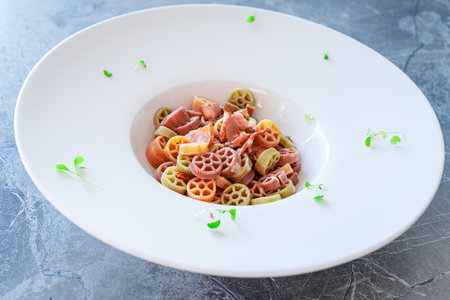 Rotelle pasta in different colors on a white plate with wide sides is decorated with microgreens. High quality photoの写真素材