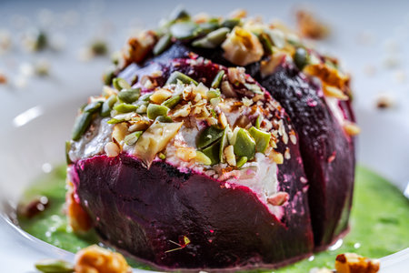 Beetroot with cottage cheese cream, nuts and pumpkin seeds on green spinach sauce is served on a white plate. Serving of a healthy dish. Close-up. High quality photoの写真素材