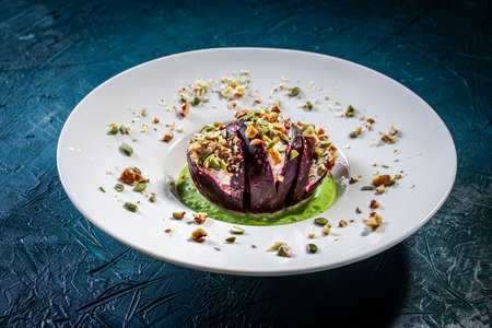 Beetroot with cottage cheese cream, nuts and pumpkin seeds on green spinach sauce served on a white plate. Restaurant presentation of a healthy dish. High quality photoの写真素材