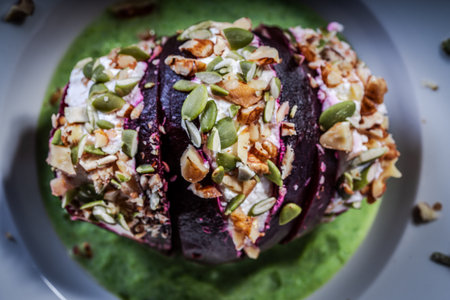 Beetroot with cottage cheese cream, nuts and pumpkin seeds on green spinach sauce served on a white plate. Concept healthy food - beautiful. Restaurant serving. Close-up. Top view. High quality photoの写真素材