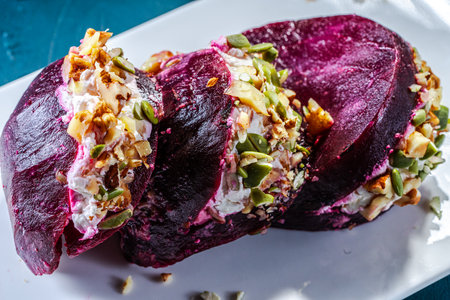 Pieces of beetroot stuffed with cream cheese and nuts on a white plate with pumpkin seeds on a green malachite background. High quality photoの写真素材