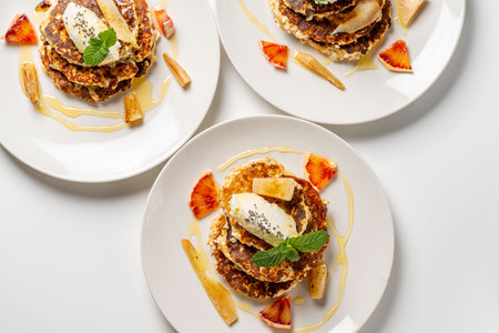 Cottage cheese pancakes with cream cheese, orange, honey and mint on a white plate and background. Healthy, dietary breakfast. Top view. High quality photoの写真素材