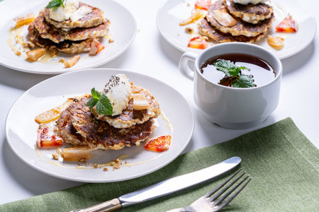 Cottage cheese pancakes with orange and chia seeds on a white plate with a cup of tea and mint on a light background. The concept of a healthy, dietary breakfast at home. High quality photoの写真素材