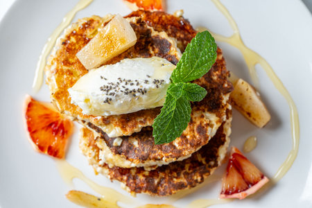 Cottage cheese pancakes with cream cheese, orange, honey and mint on a white plate and background. Healthy, dietary breakfast. Top view. Close up. High quality photoの写真素材