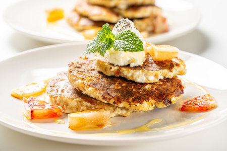 Healthy, dietary breakfast. Cottage cheese pancakes with cream cheese, orange, honey and mint on a white plate and background. High quality photoの写真素材