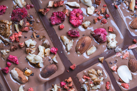 Handmade chocolate close-up. Assorted chocolate with almonds, freeze-dried raspberries and strawberries. . Background for using banners and menus. High quality photoの写真素材
