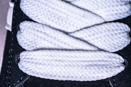 Lace-up on sneakers close-up. White, wide laces in black sneakers.の写真素材