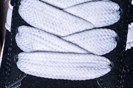 Lace-up on sneakers close-up. White, wide laces in black sneakers. High quality photoの写真素材