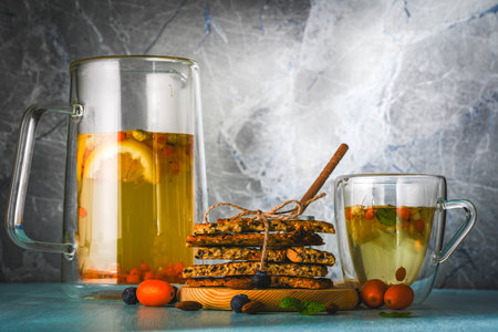 Flax and sesame seed crackers on a wooden board with sea buckthorn tea with honey, blueberries and kumquat on a blue background. Healthy, vegetarian breakfast. High quality photoの写真素材