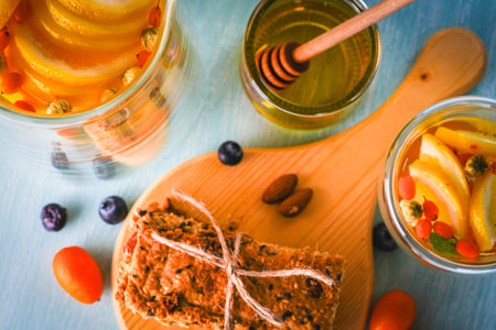 Flax and sesame seed crackers on a wooden board with sea buckthorn tea with honey, blueberries and kumquat on a blue background. Healthy, vegetarian breakfast. Top view. High quality photoの写真素材