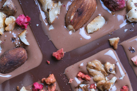 The process of making homemade chocolate. Nuts, freeze-dried raspberries and strawberries are laid out on liquid chocolate. High quality photoの写真素材