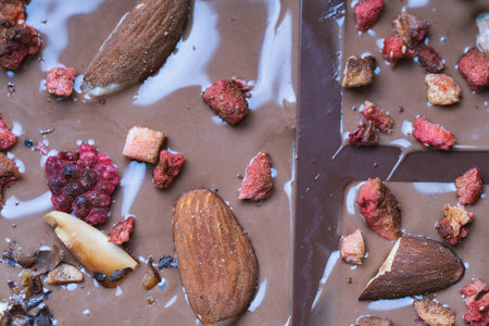 The process of making homemade chocolate. Nuts, freeze-dried raspberries and strawberries are laid out on liquid chocolate. High quality photoの写真素材