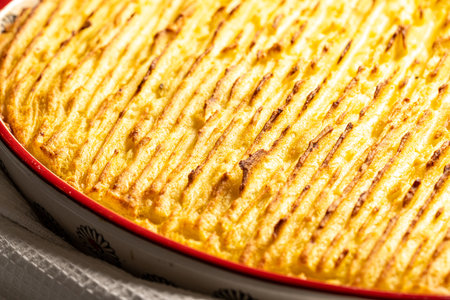 Potato casserole in a porcelain, red baking dish with a white towel on a gray background. Close-up. High quality photoの写真素材
