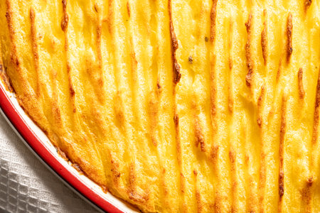 Potato casserole in a porcelain, red baking dish with a white towel on a gray background. Close-up. High quality photoの写真素材