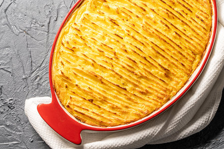 Potato casserole in a porcelain, red baking dish with a white towel on a gray background. Close-up. High quality photo. Top view.の写真素材