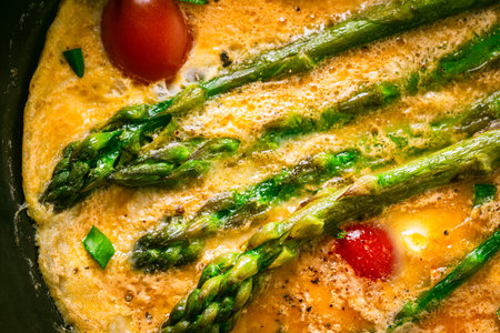 Close-up of an omelet with asparagus and tomatoes. Background with food texture. Use for a menu or banner. View from above. Flat layout. High quality photoの写真素材