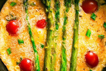 Close-up of an omelet with asparagus and tomatoes. Background with food texture. Use for a menu or...
