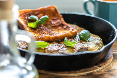 Traditional spanish breakfast potato tortilla and tostado pan con tomate. Potatoes and croutons with garlic and tomato sauce in a cast iron frying pan on a rustic wooden background. High quality photoの写真素材