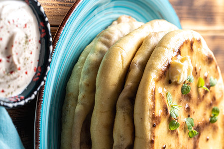 Khychins, traditional Caucasian, Eastern dish. Flatbread stuffed with minced meat with sauce on a turquoise plate with cutlery and a napkin on a wooden table. Close-up. High quality photoの写真素材