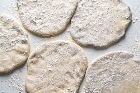 Raw flatbreads on a white table with flour.の写真素材