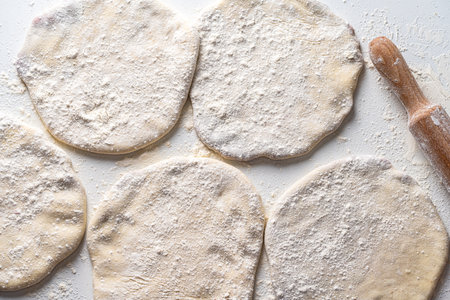 Raw Khychins, traditional Caucasian, Eastern dish. Flatbread stuffed with minced meat on a white table with flour and a rolling pin. Ready to fry. High quality photoの写真素材