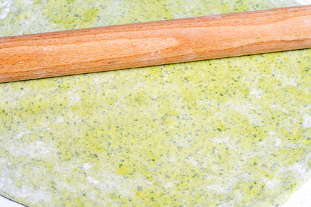 Green dough rolled out on the table and a rolling pin. Bake healthy pizza. Dough with spinach and basil. High quality photoの写真素材