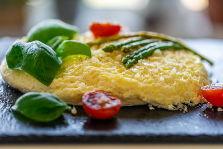 Omelet with baked asparagus, tomatoes and basil. Close-up, background. For use in menus and banners. The concept of a delicious and healthy breakfast. High quality photoの写真素材